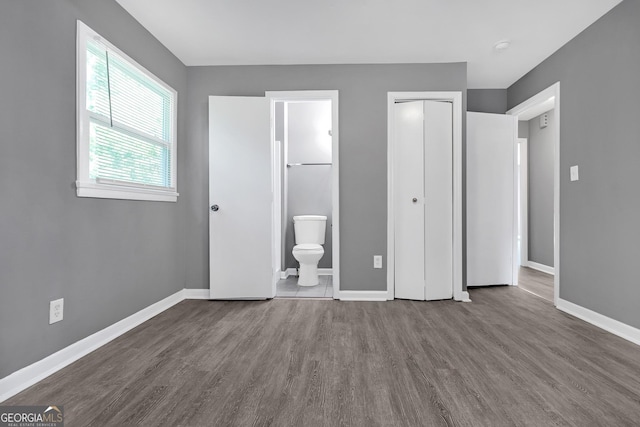 unfurnished bedroom with hardwood / wood-style flooring, a closet, and ensuite bath