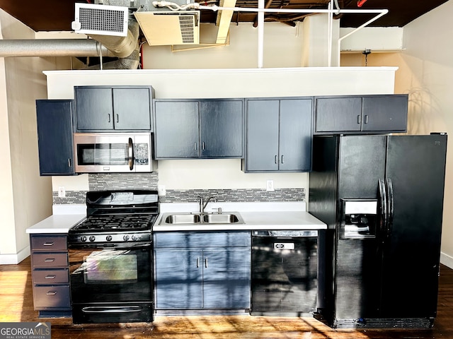 kitchen with black appliances, decorative backsplash, sink, and hardwood / wood-style flooring