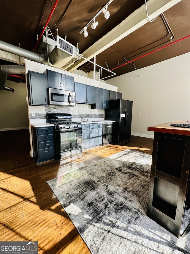 kitchen featuring black appliances, dark hardwood / wood-style floors, sink, and backsplash