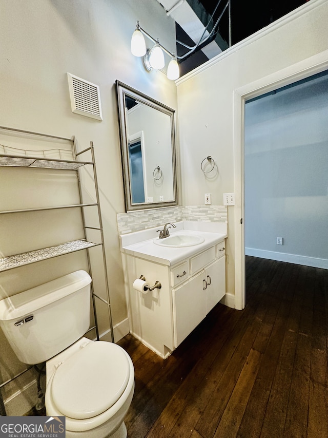 bathroom with tasteful backsplash, toilet, vanity, and hardwood / wood-style flooring