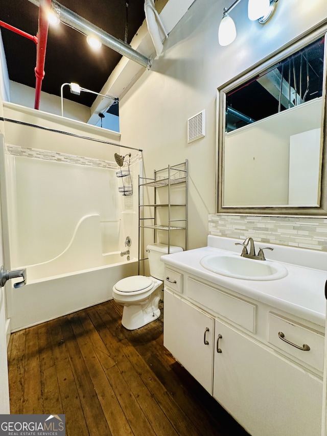 full bathroom with bathing tub / shower combination, toilet, decorative backsplash, vanity, and hardwood / wood-style flooring