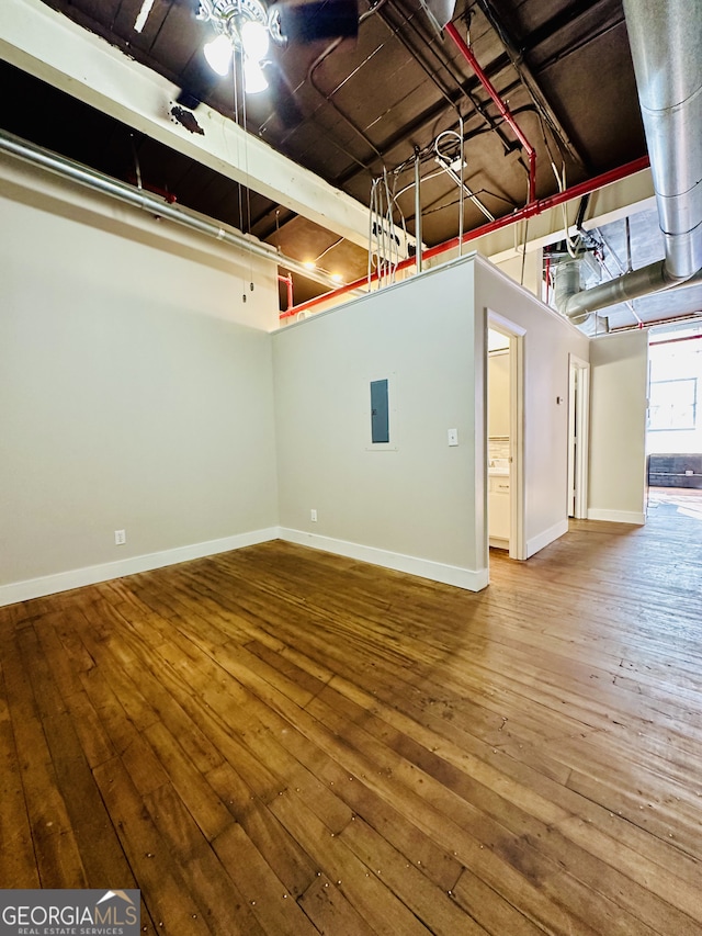 basement featuring hardwood / wood-style floors, ceiling fan, and electric panel