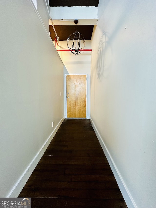 corridor featuring dark hardwood / wood-style flooring and a notable chandelier