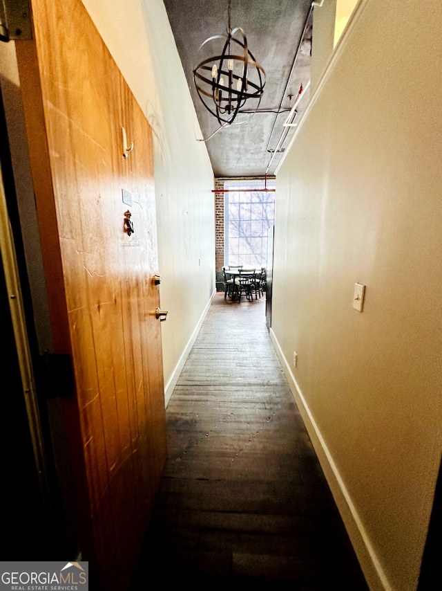 hallway featuring dark wood-type flooring and a notable chandelier