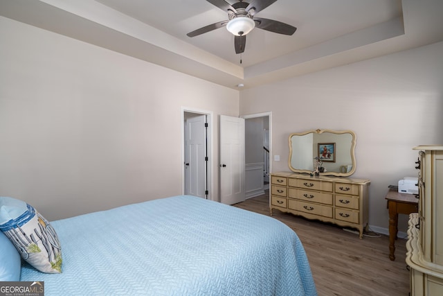 bedroom featuring hardwood / wood-style flooring, ceiling fan, and a raised ceiling