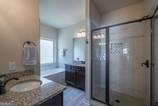 bathroom featuring wood-type flooring, vanity, and shower with separate bathtub