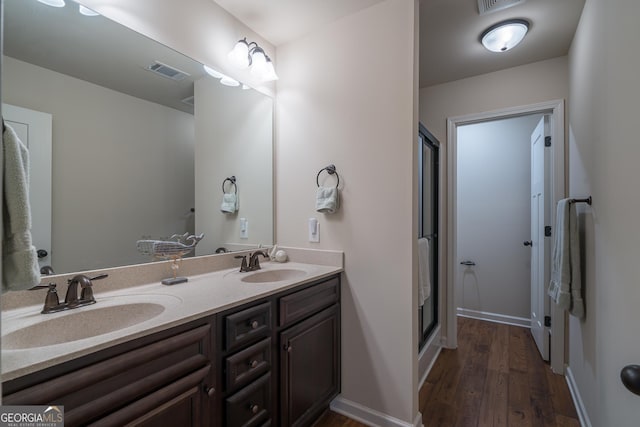 bathroom with hardwood / wood-style flooring, vanity, and a shower with door