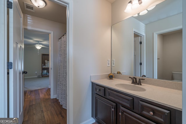 bathroom with hardwood / wood-style floors, vanity, toilet, and ceiling fan