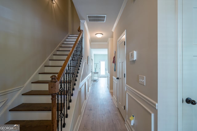 stairs featuring wood-type flooring and ornamental molding