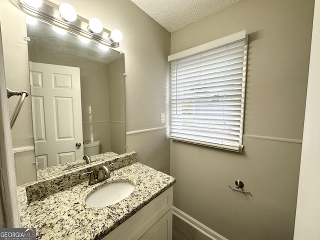 bathroom with vanity, a textured ceiling, and toilet