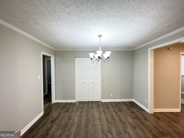 unfurnished dining area with dark hardwood / wood-style floors, ornamental molding, a textured ceiling, and an inviting chandelier