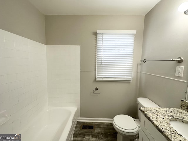 bathroom with hardwood / wood-style floors, a washtub, toilet, and vanity