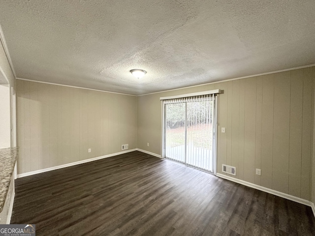 unfurnished room featuring a textured ceiling, crown molding, dark wood-type flooring, and wood walls