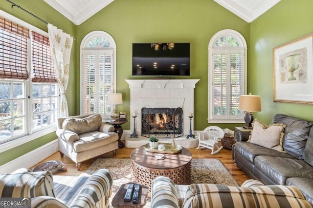 living room with a wealth of natural light, vaulted ceiling, and hardwood / wood-style flooring