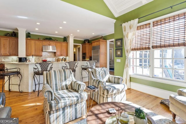 living room featuring lofted ceiling, light hardwood / wood-style flooring, and crown molding