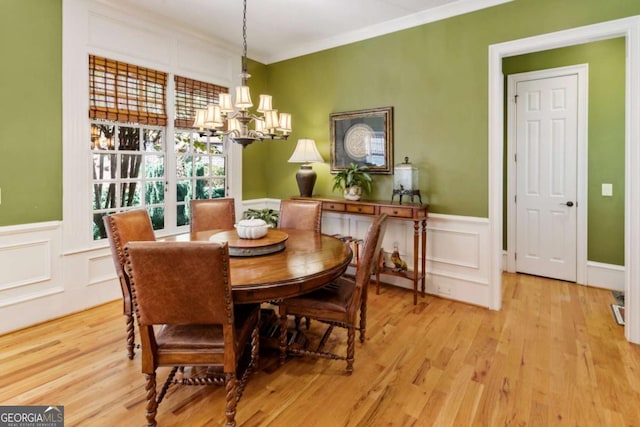 dining space with crown molding, light hardwood / wood-style floors, and an inviting chandelier