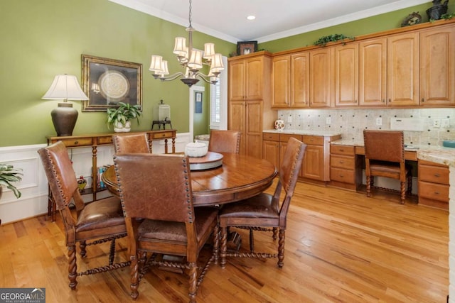 dining area featuring light wood-type flooring, an inviting chandelier, and ornamental molding