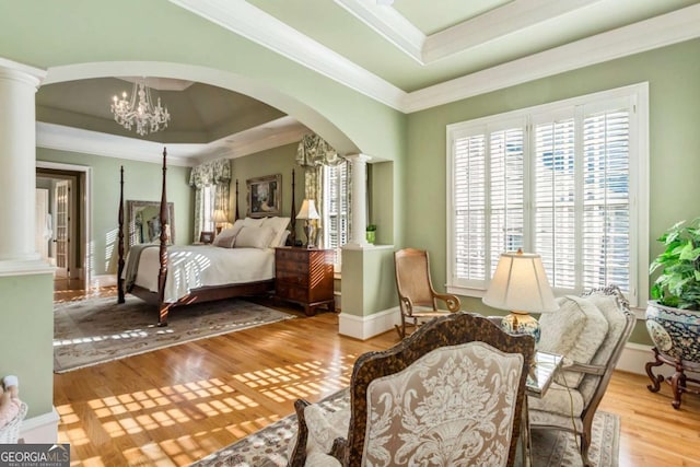 bedroom featuring decorative columns, multiple windows, and light hardwood / wood-style floors