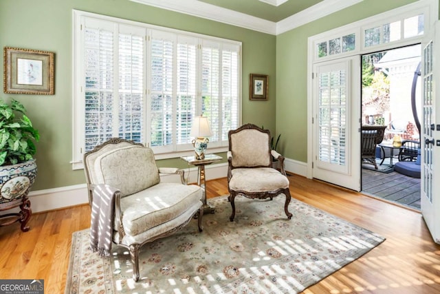 living area featuring a healthy amount of sunlight, crown molding, and light hardwood / wood-style flooring