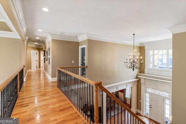 corridor featuring an inviting chandelier, light hardwood / wood-style floors, and ornamental molding