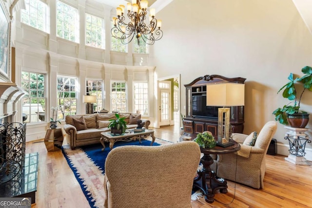 living room featuring a towering ceiling, wood-type flooring, and a notable chandelier