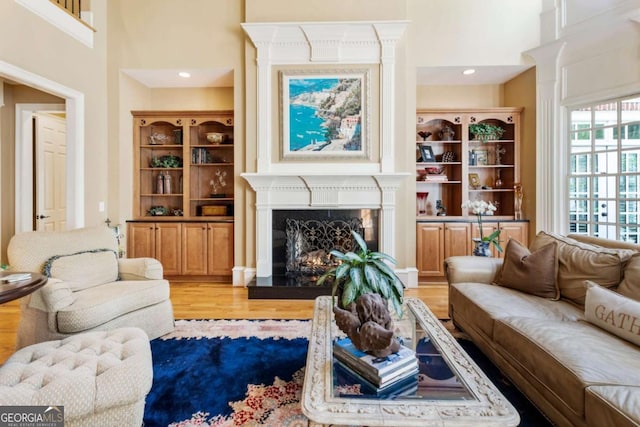 living room featuring a high ceiling, light wood-type flooring, and a premium fireplace