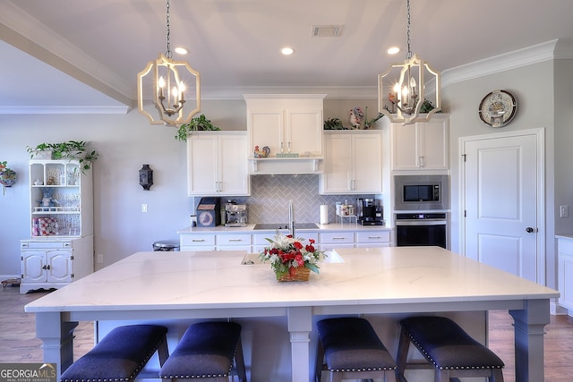 kitchen with a center island with sink, white cabinets, a breakfast bar area, and tasteful backsplash