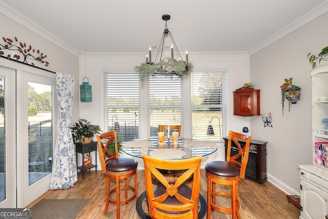 dining room with ornamental molding, light wood-type flooring, and french doors