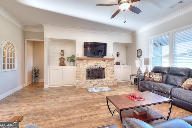 living room featuring a fireplace, ceiling fan, crown molding, and light hardwood / wood-style flooring