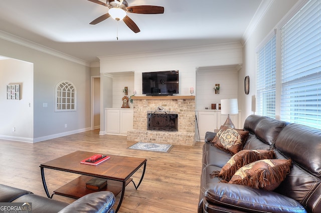 living room with a fireplace, light wood-type flooring, ceiling fan, and ornamental molding