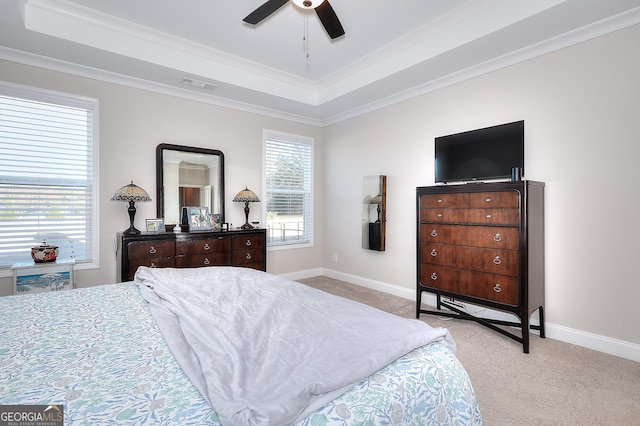 carpeted bedroom featuring ceiling fan, crown molding, and a tray ceiling