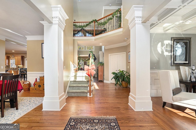 entrance foyer with coffered ceiling, wood-type flooring, ornamental molding, and decorative columns