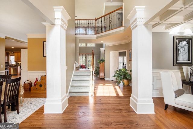 foyer entrance with a healthy amount of sunlight, wood-type flooring, and ornate columns