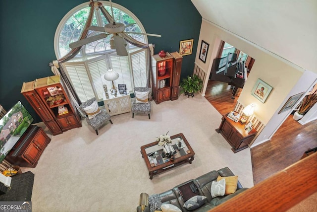 living room with a towering ceiling, carpet floors, and ceiling fan