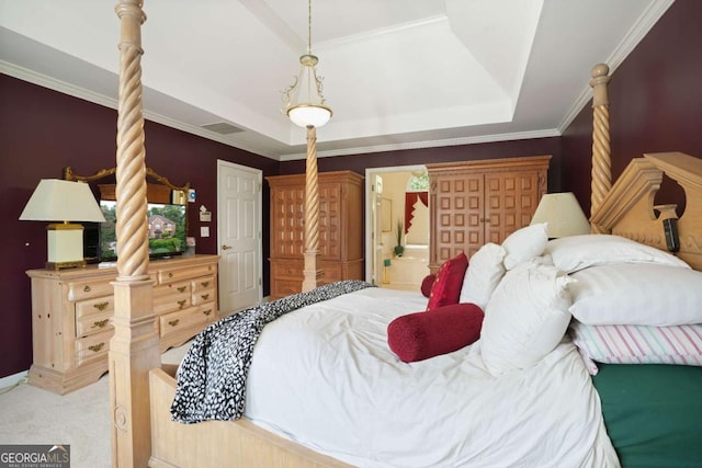 carpeted bedroom featuring a tray ceiling, ensuite bath, and ornamental molding