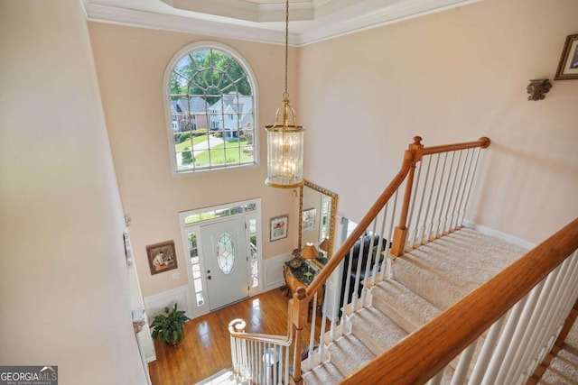 entryway with hardwood / wood-style flooring, crown molding, and a chandelier