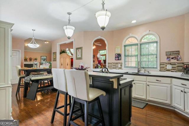 kitchen with sink, white cabinets, dark wood-type flooring, and decorative light fixtures