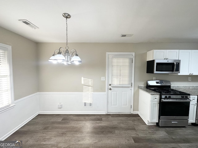 kitchen featuring dark wood-type flooring, hanging light fixtures, a notable chandelier, white cabinets, and appliances with stainless steel finishes