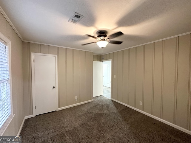 carpeted spare room featuring a textured ceiling, ceiling fan, and crown molding