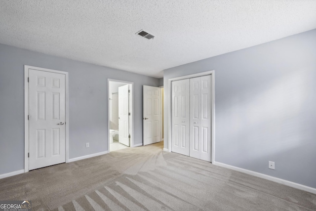 unfurnished bedroom featuring connected bathroom, light colored carpet, and a textured ceiling