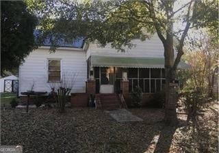 back of house featuring a sunroom and a storage shed