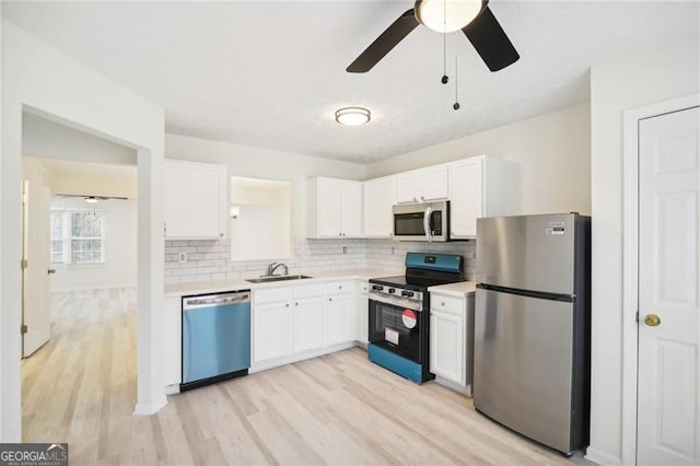 kitchen with light wood-type flooring, white cabinetry, and stainless steel appliances