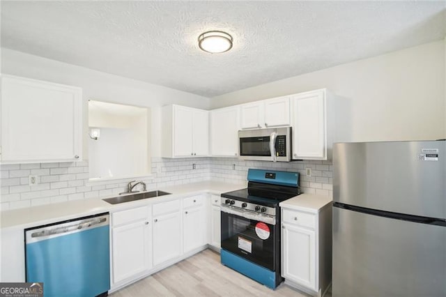 kitchen with white cabinetry, sink, light hardwood / wood-style flooring, and appliances with stainless steel finishes