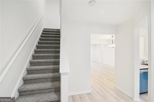 staircase with wood-type flooring and an inviting chandelier