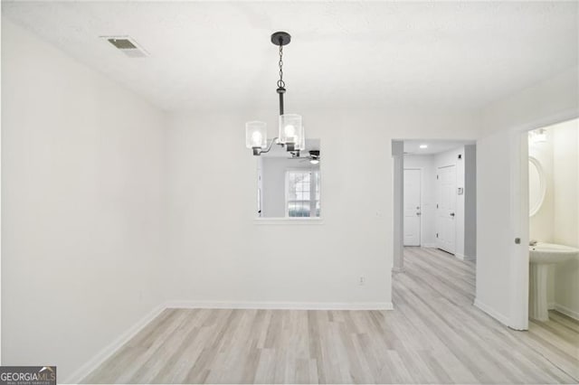 unfurnished dining area featuring light wood-type flooring and a chandelier