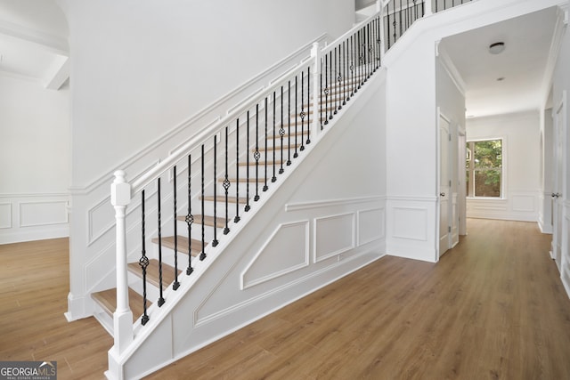 staircase with hardwood / wood-style flooring and crown molding