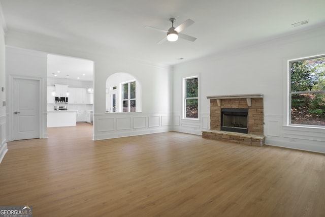 unfurnished living room featuring crown molding, a fireplace, and light wood-type flooring