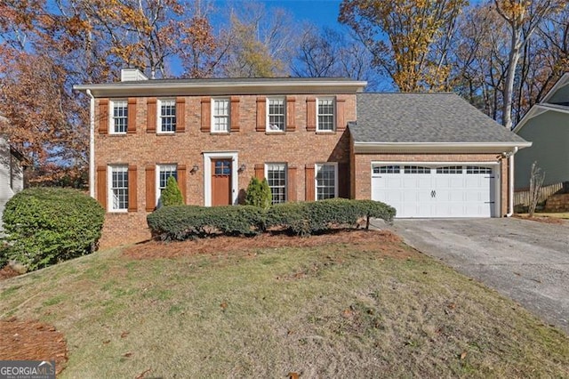 colonial-style house featuring a garage and a front lawn