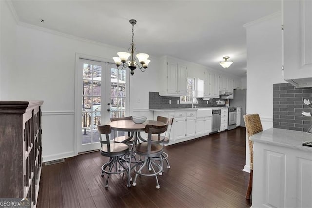 dining space with french doors, an inviting chandelier, dark wood-type flooring, and ornamental molding