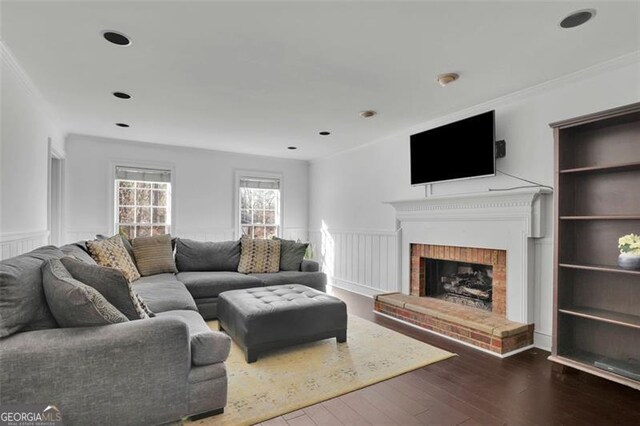 living room featuring a fireplace, crown molding, built in features, and dark wood-type flooring